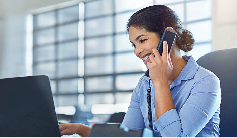 Woman working on a laptop and talking on the phone while managing a US company remotely.